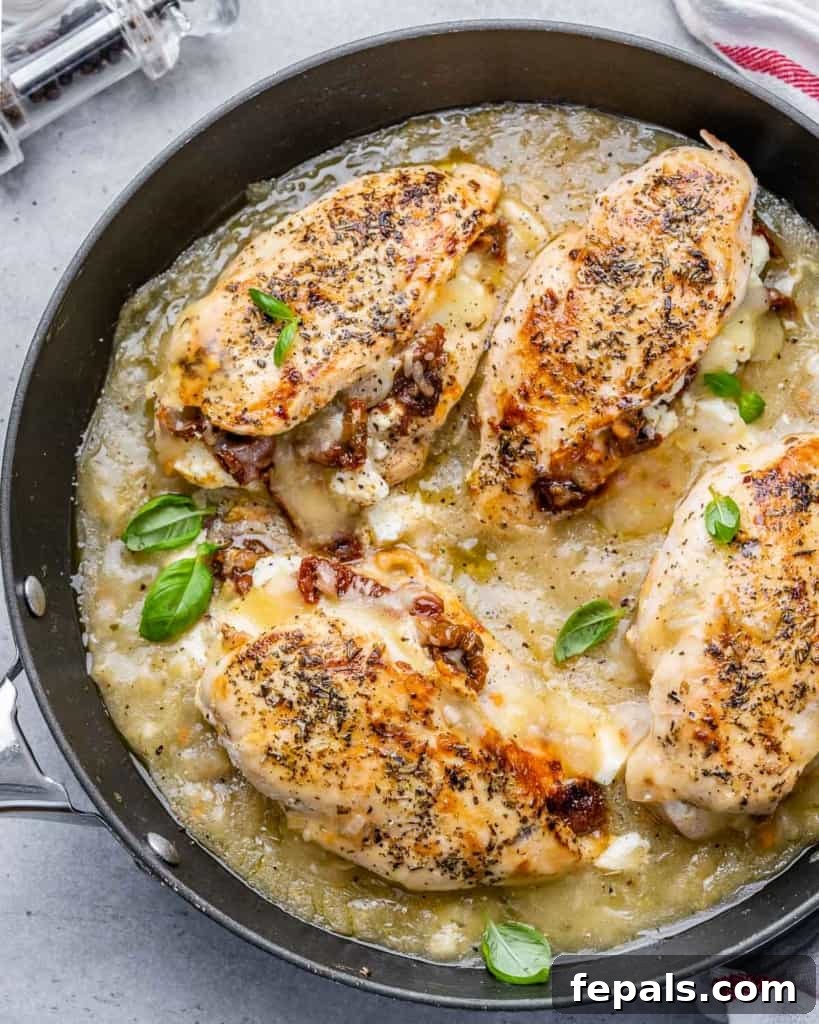 Savory Sun-dried Tomatoes and Cheese Stuffed Chicken 3 Top view of perfectly cooked stuffed chicken breasts simmering in a rich, savory sauce within a black skillet, highlighting the delicious golden crust.