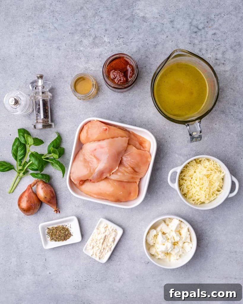 Savory Sun-dried Tomatoes and Cheese Stuffed Chicken 4 A flat lay photograph showcasing all the fresh ingredients needed for the cheese and tomato stuffed chicken breast: raw chicken breasts, a bowl of mixed cheeses and sun-dried tomatoes, herbs, a bottle of stock, fresh basil, and diced shallots.