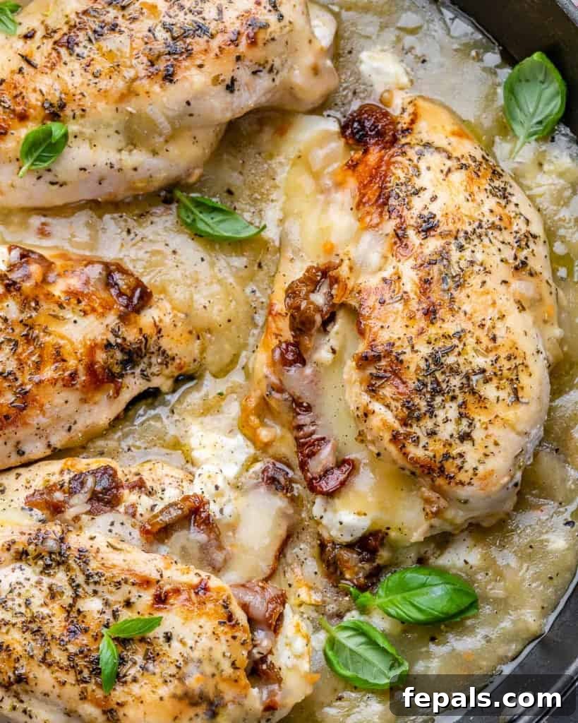 Savory Sun-dried Tomatoes and Cheese Stuffed Chicken 6 Top view close-up image of two perfectly seared and sauced stuffed chicken breasts in a black skillet, ready to be served.