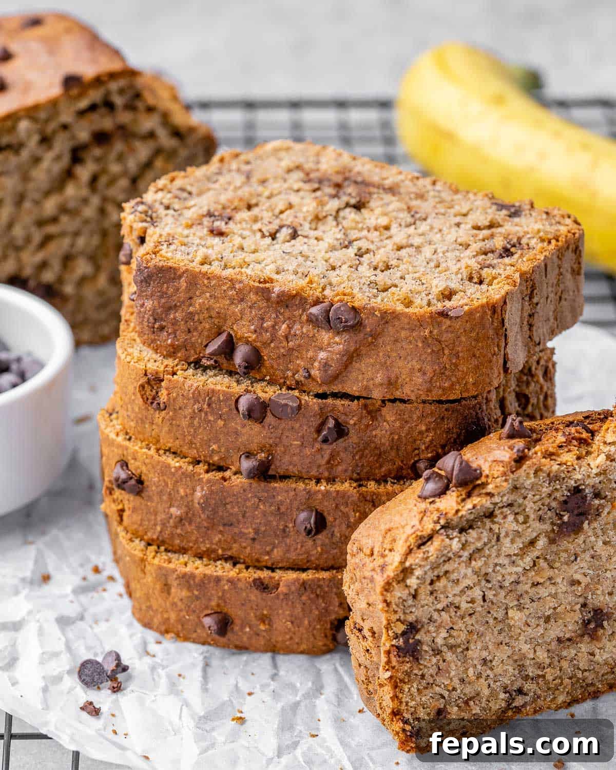 A stack of perfectly sliced vegan banana bread, showcasing its fluffy texture and abundance of chocolate chips.