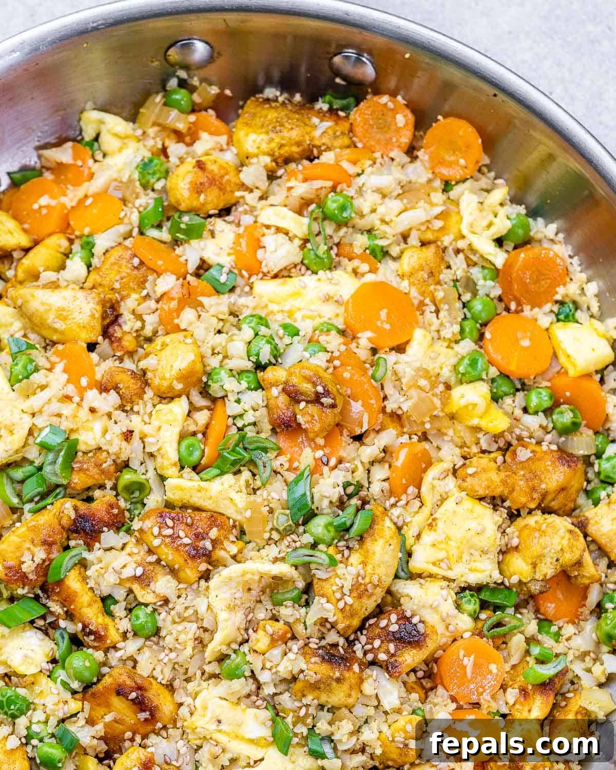 Healthy cauliflower fried rice with chicken and a variety of colorful vegetables in a serving bowl