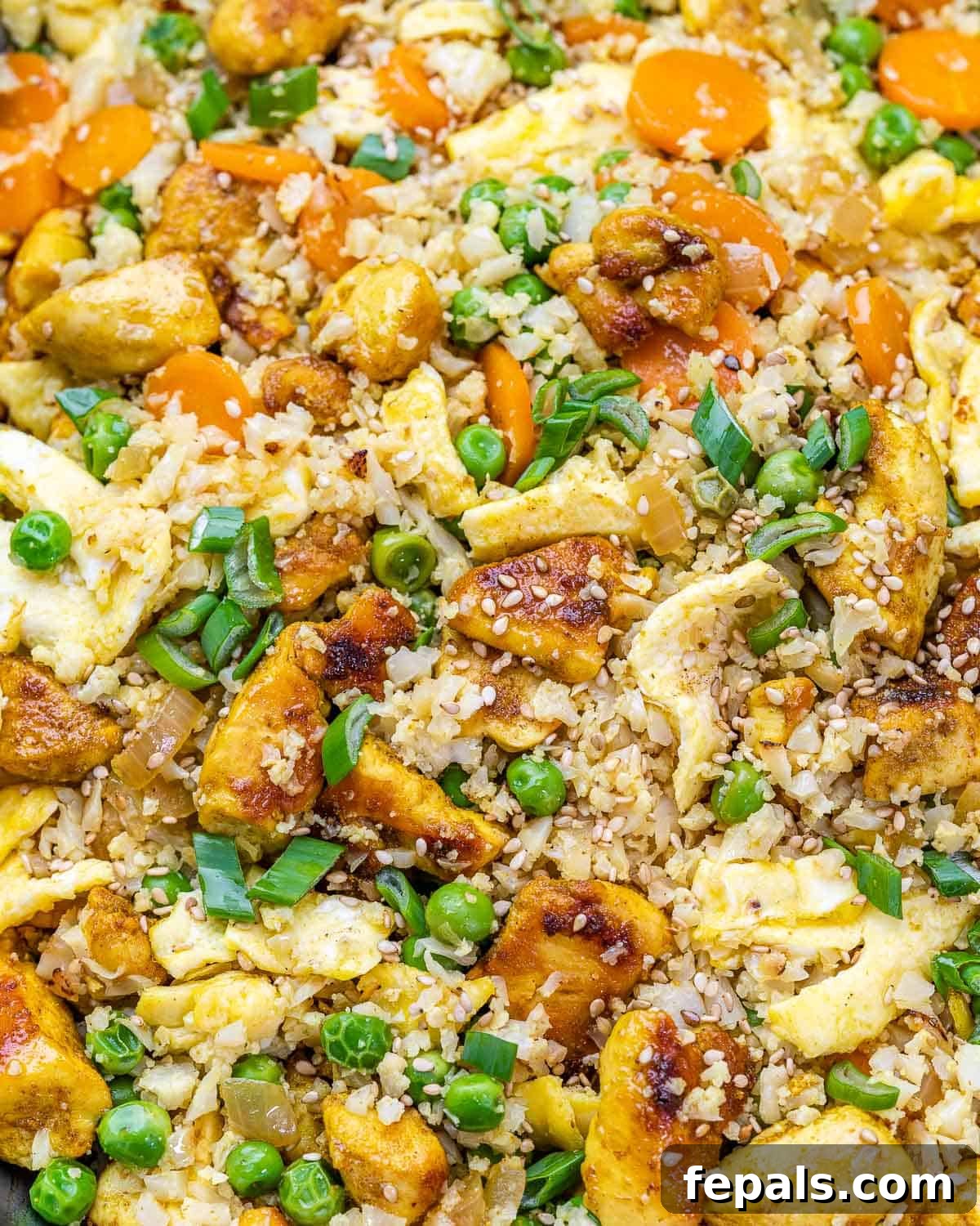 Close-up view of vibrant chicken cauliflower fried rice with visible veggies and scrambled egg