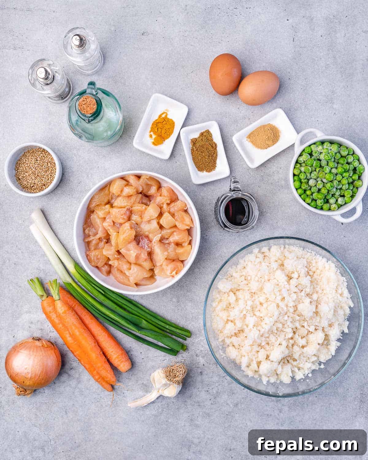 Ingredients for Healthy Chicken Cauliflower Fried Rice: eggs, turmeric, ginger, peas, cauliflower rice, carrots, green onions, coconut aminos, oil, salt, pepper, chicken, garlic, onion, sesame seeds