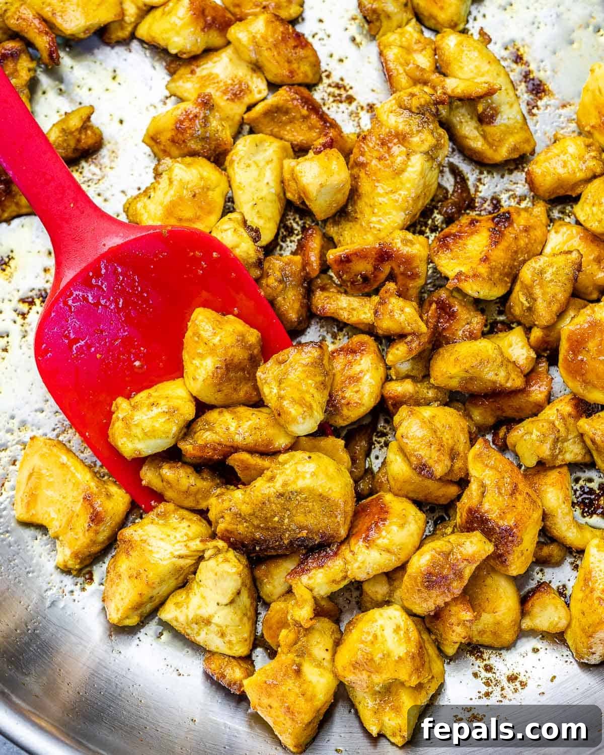 Cooked chicken breast pieces in a skillet, seasoned with spices