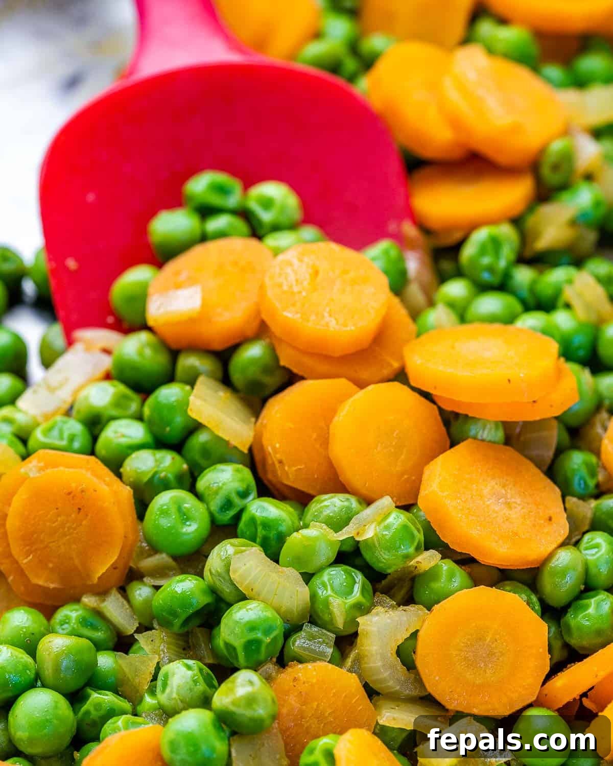 Sliced carrots and peas sizzling in a skillet, ready for cauliflower rice