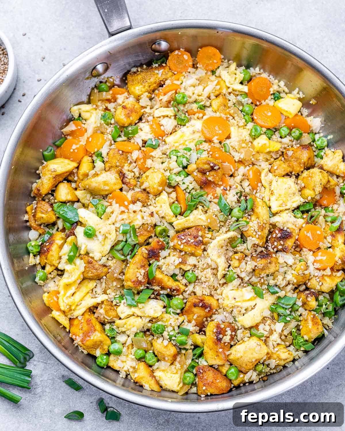 Skillet full of savory chicken fried rice and cauliflower with a medley of vegetables