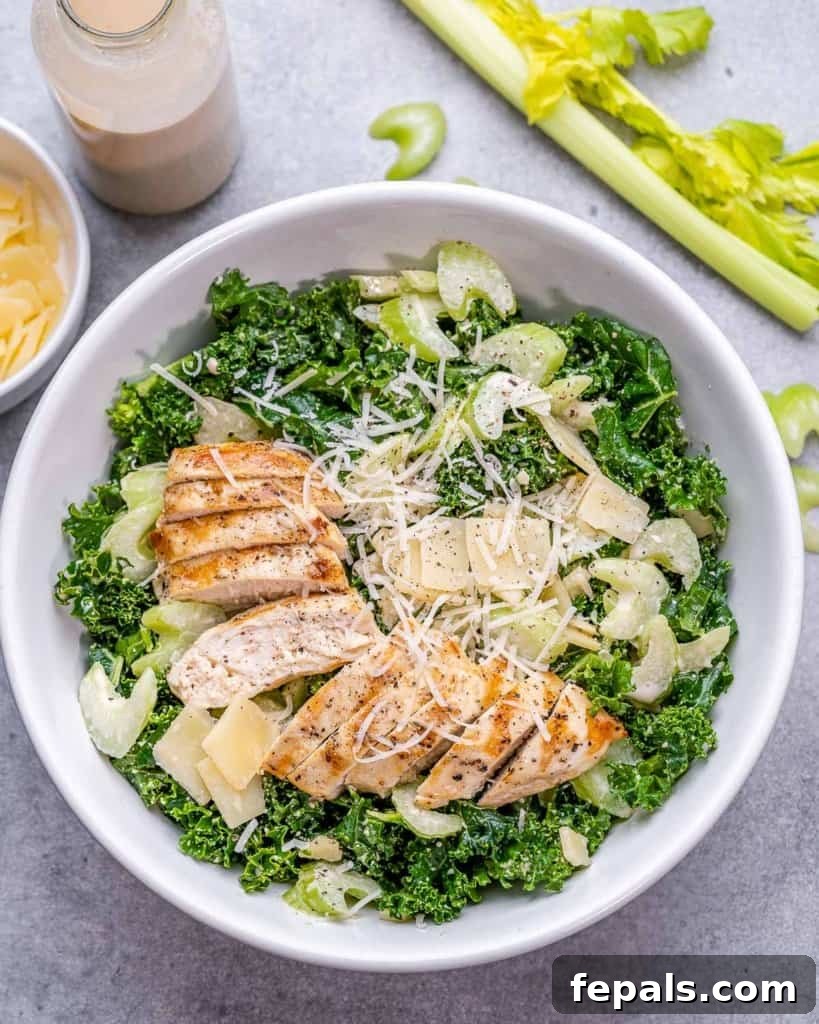 Flame-Kissed Chicken Kale Caesar 2 top view kale salad with sliced chicken breast in a white bowl with a side of dressing