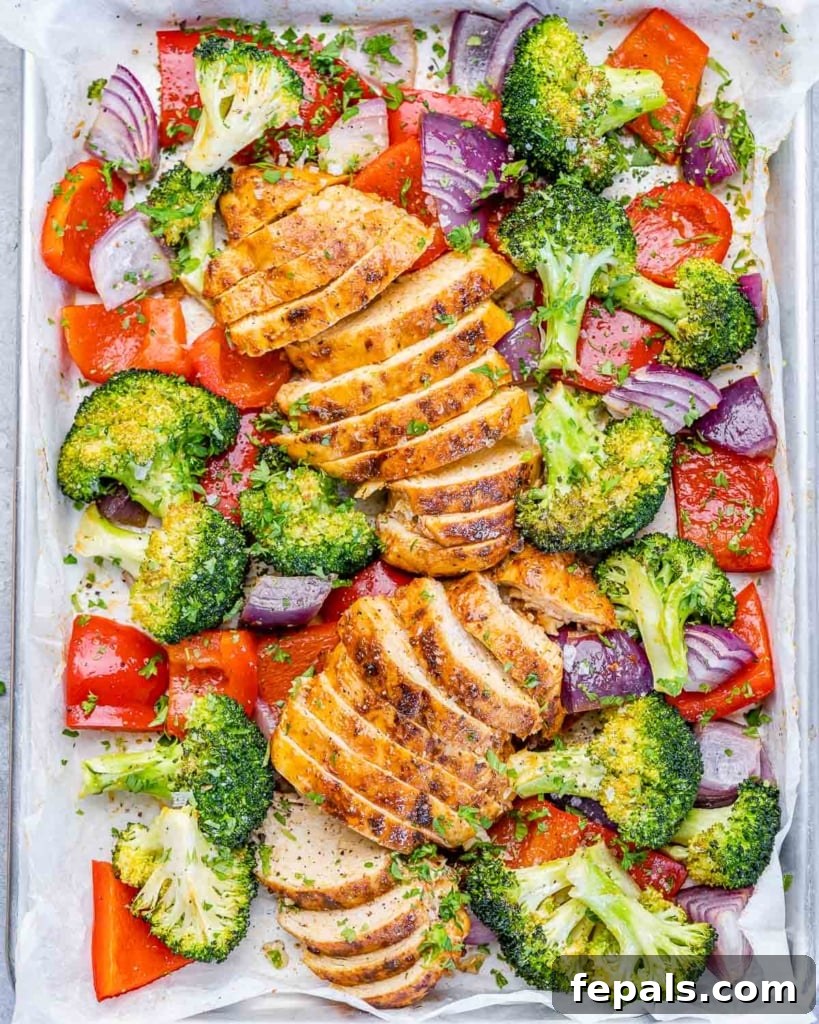top view sliced baked chicken breast with roasted veggies on a sheet pan