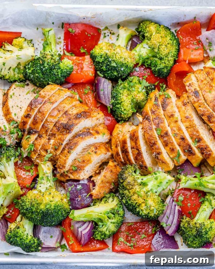 sliced baked chicken breast with roasted veggies on a pan 