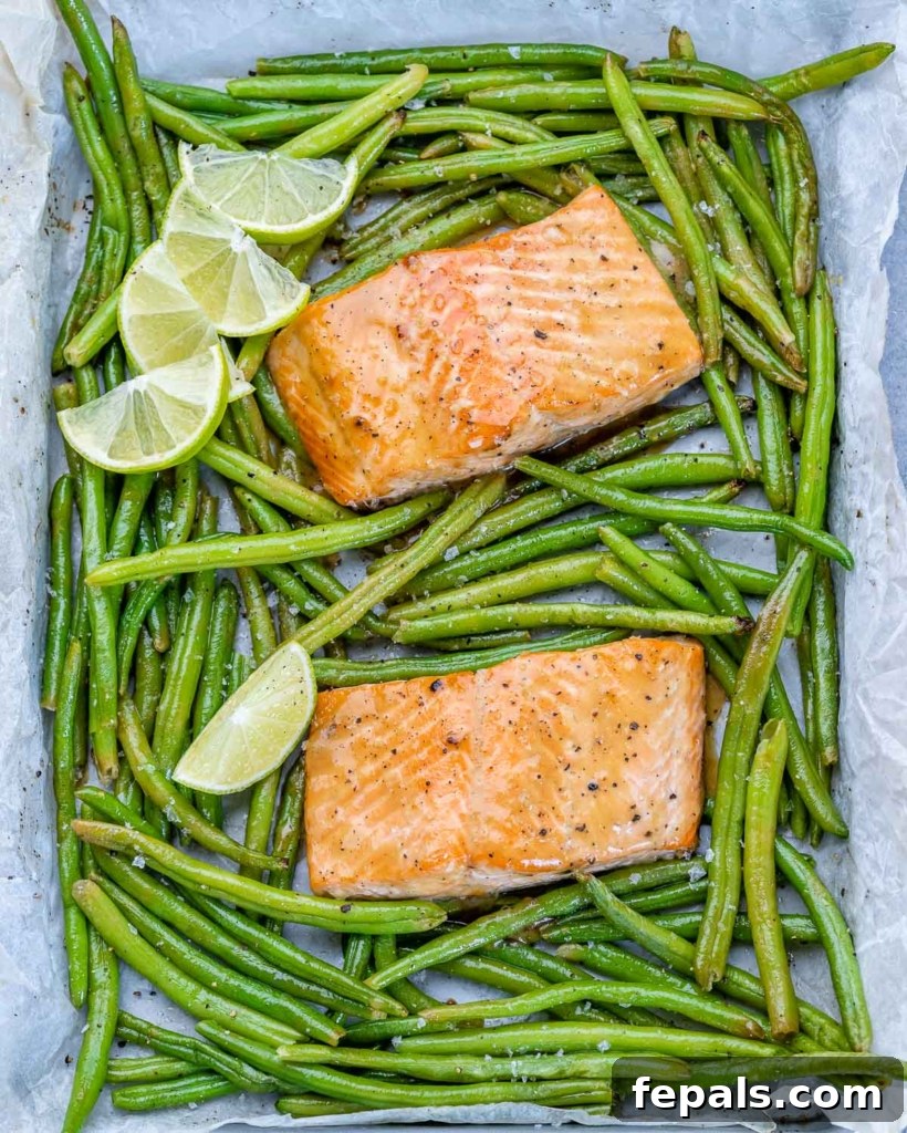 salmon filets on pan with green beans around them and lime garnishes on top left 