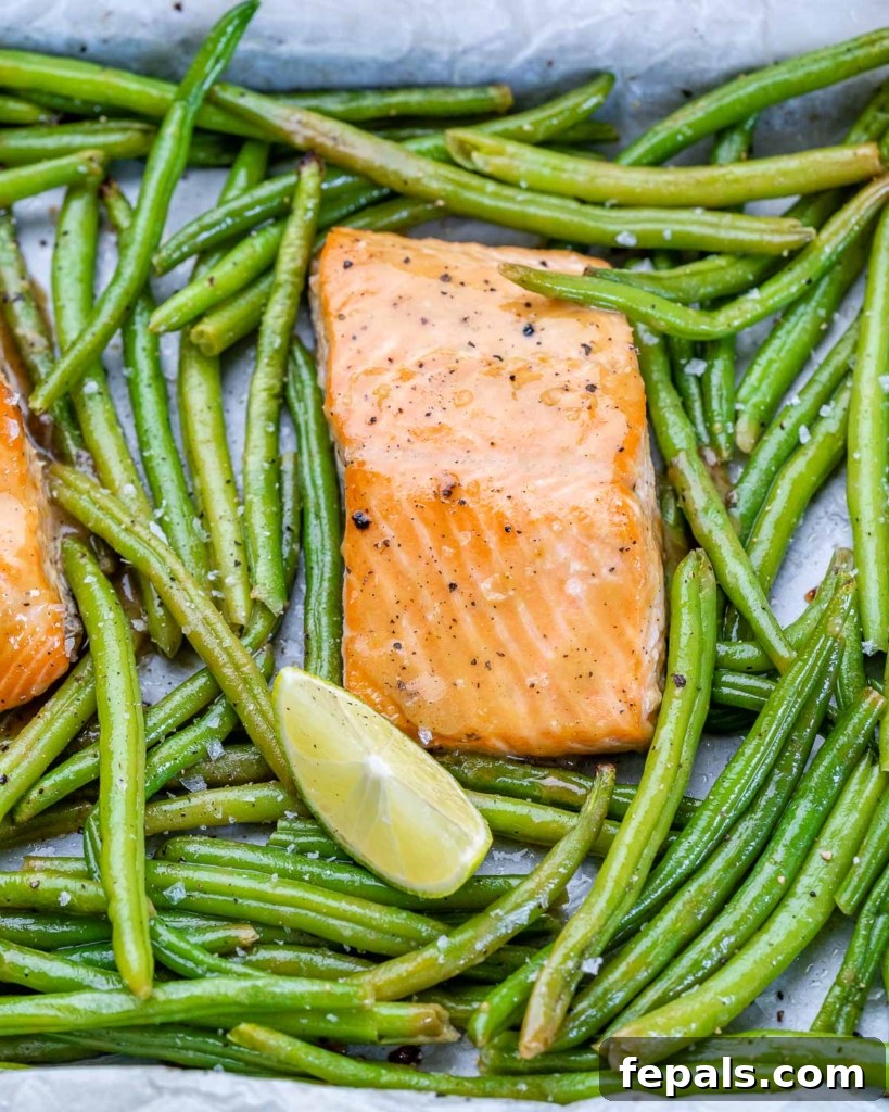 a single baked salmon filet with maple glaze on a sheet pan with green beans around it
