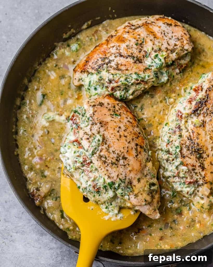 Tuscan Cheese-Stuffed Chicken 2 Deliciously golden-brown Italian stuffed chicken breasts resting in a creamy sauce in a black skillet, garnished with fresh herbs