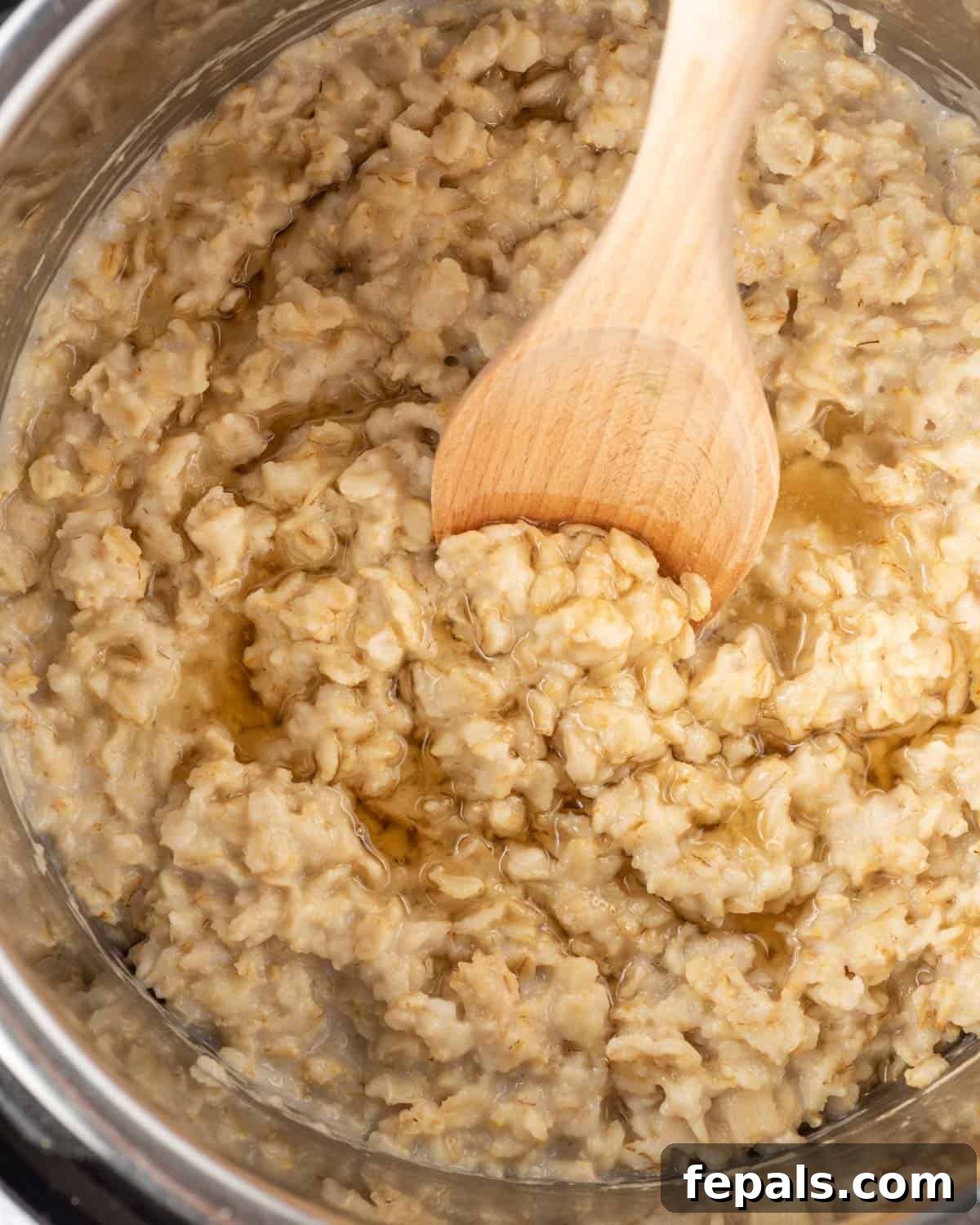 Effortless Instant Pot Oatmeal 7 wooden spoon mixing cooked oatmeal in the instant pot.