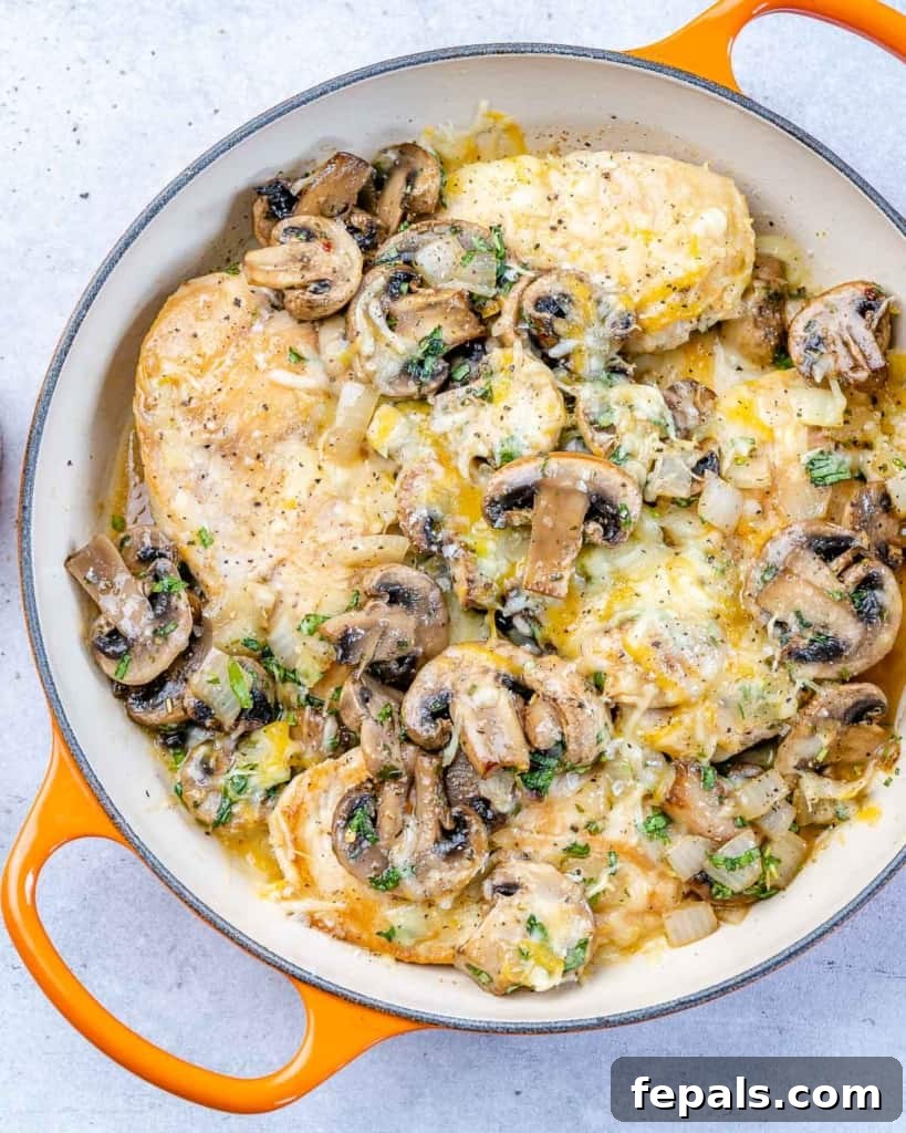 top view of cheesy chicken with mushrooms in orange skillet