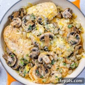 tope view of chicken breast satuteed with mushroom and topped with cheese over an orange skillet
