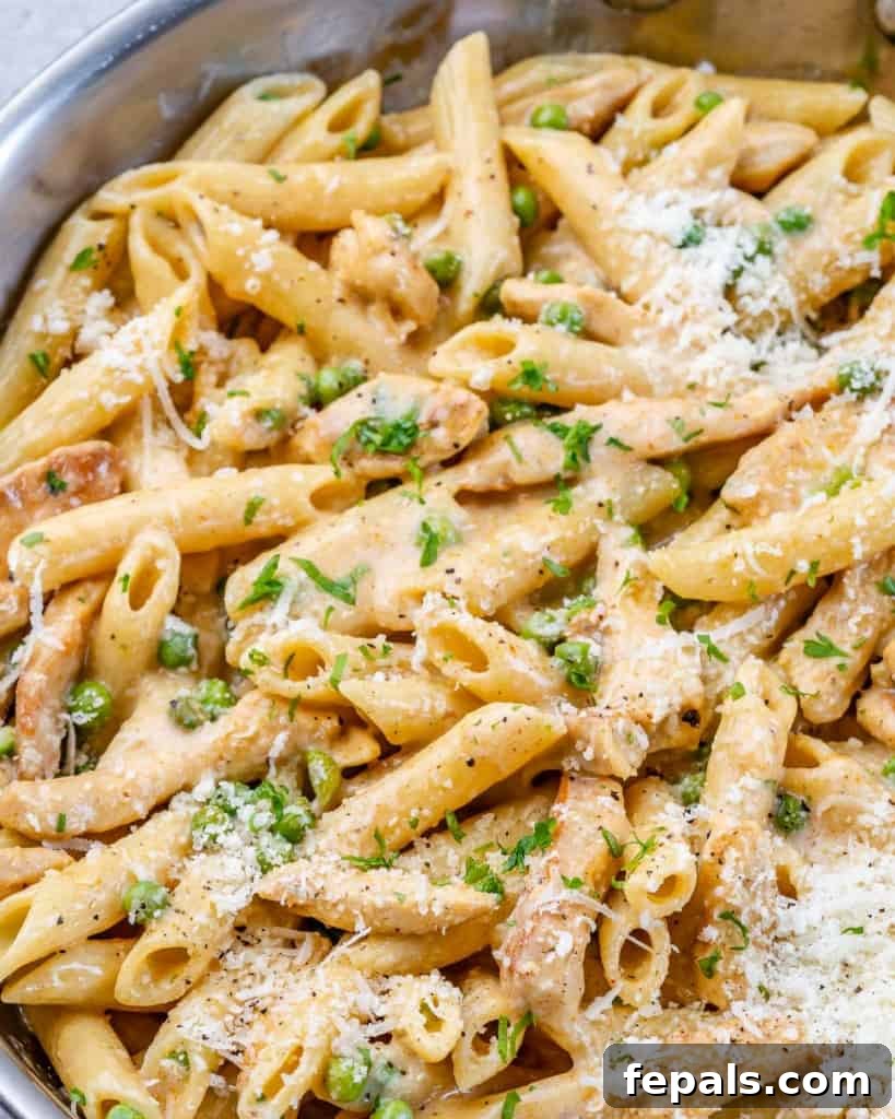 Lighter Chicken Carbonara 11 Close-up of chicken and pasta with peas, generously topped with grated Parmesan cheese and fresh parsley.