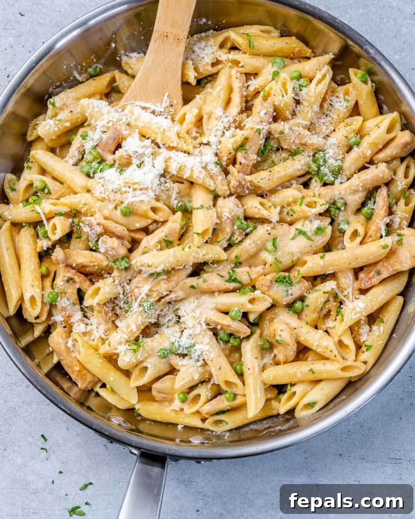 Lighter Chicken Carbonara 10 A wooden spoon rests in a skillet filled with creamy chicken and pasta, ready to be served.
