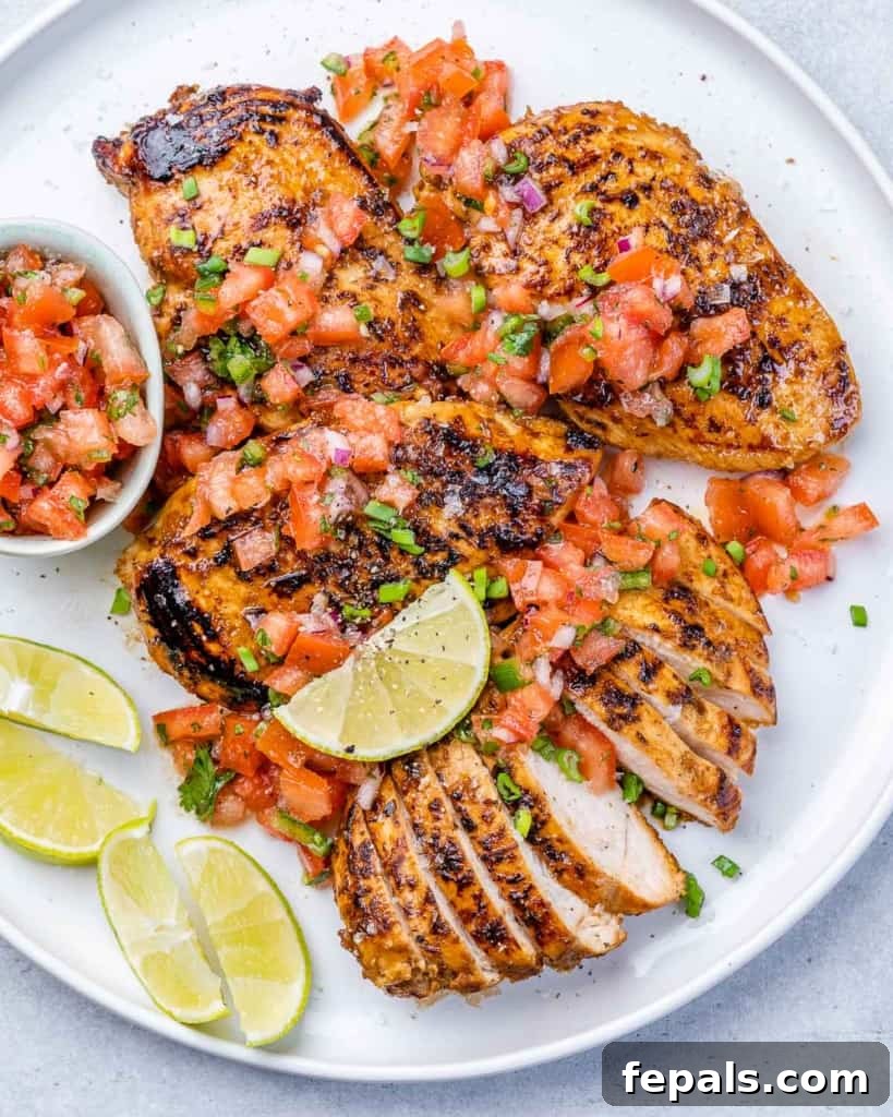 The Ultimate Jerk Chicken 2 Top view of perfectly grilled jerk chicken pieces on a white plate, garnished with fresh herbs and lime wedges.