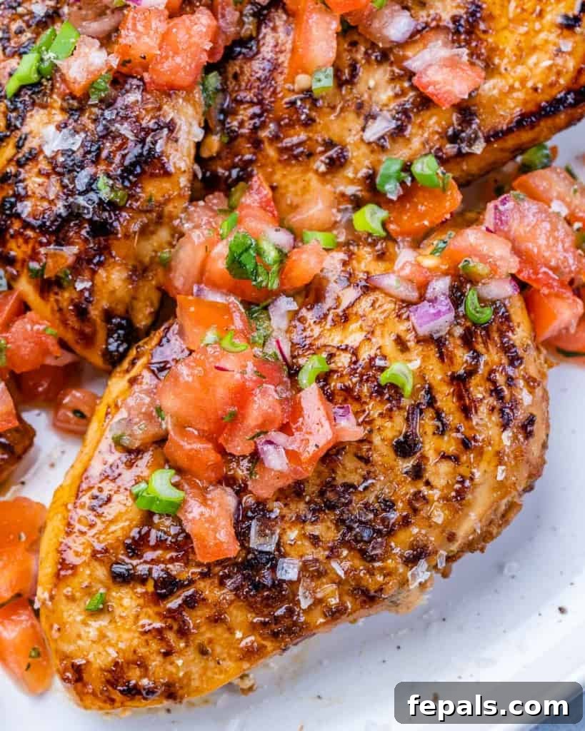 The Ultimate Jerk Chicken 8 Side shot of a perfectly grilled whole chicken breast on a plate, showcasing its golden-brown exterior.