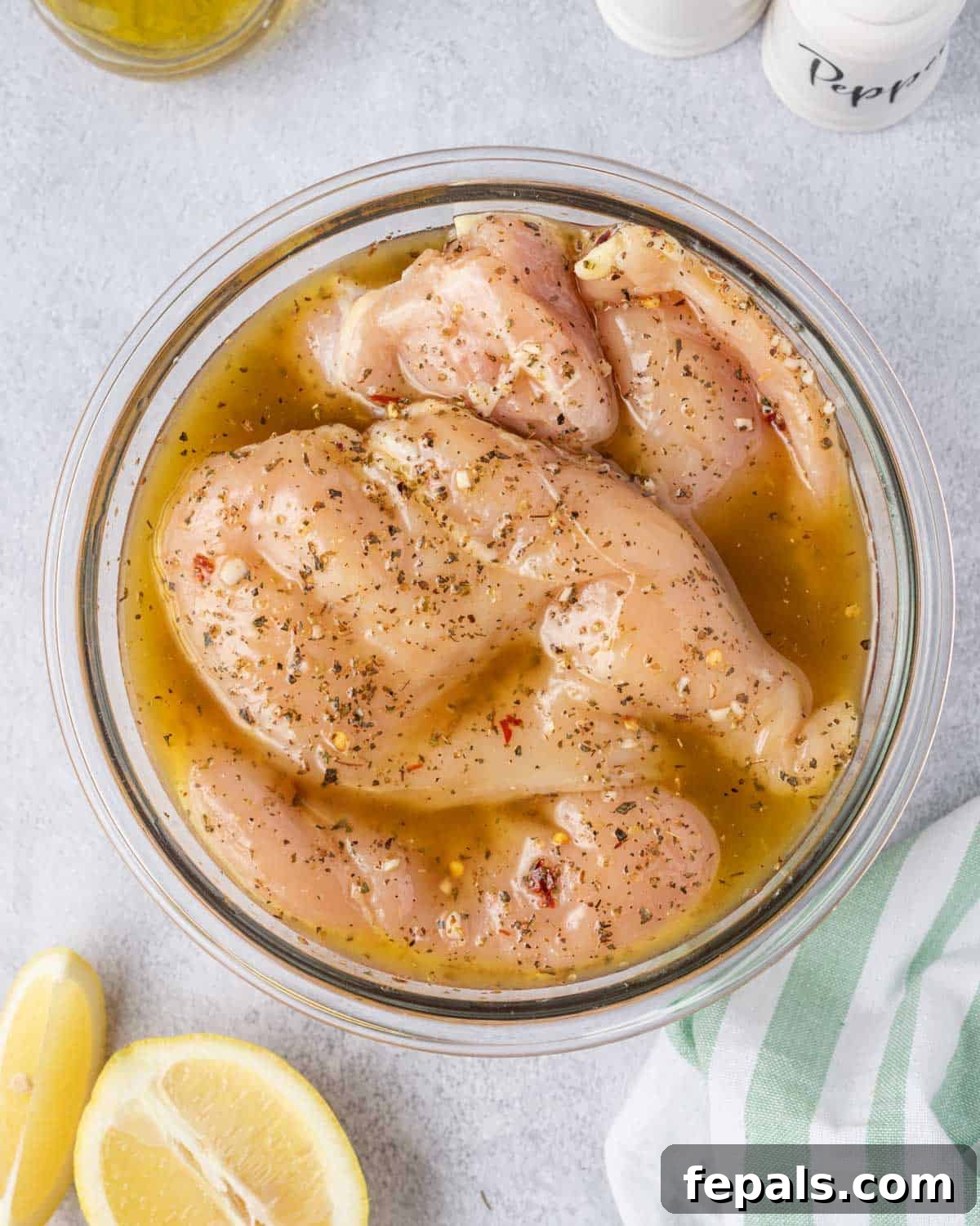 Juicy Italian Grilled Chicken Breasts 6 Raw chicken breasts submerged in the Italian marinade within a glass bowl.