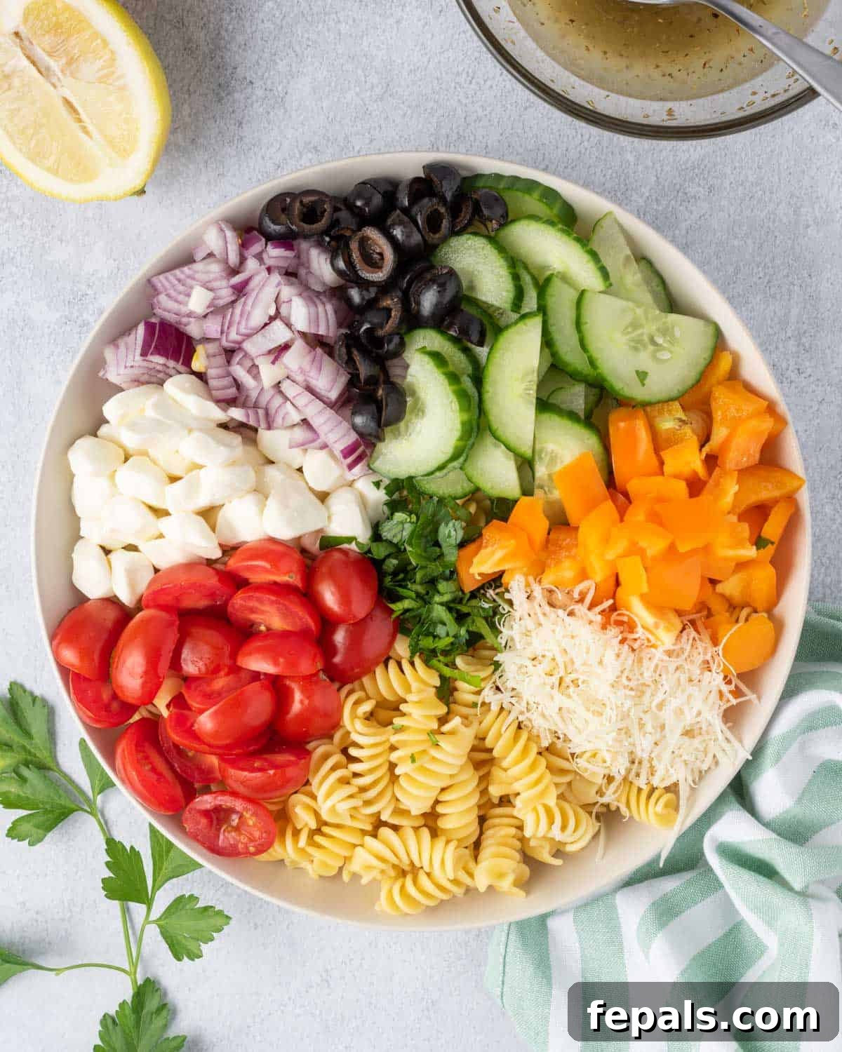 Zesty Italian Pasta Salad 8 Chopped vegetables and mozzarella pearls ready to be mixed into the pasta salad in a large bowl.