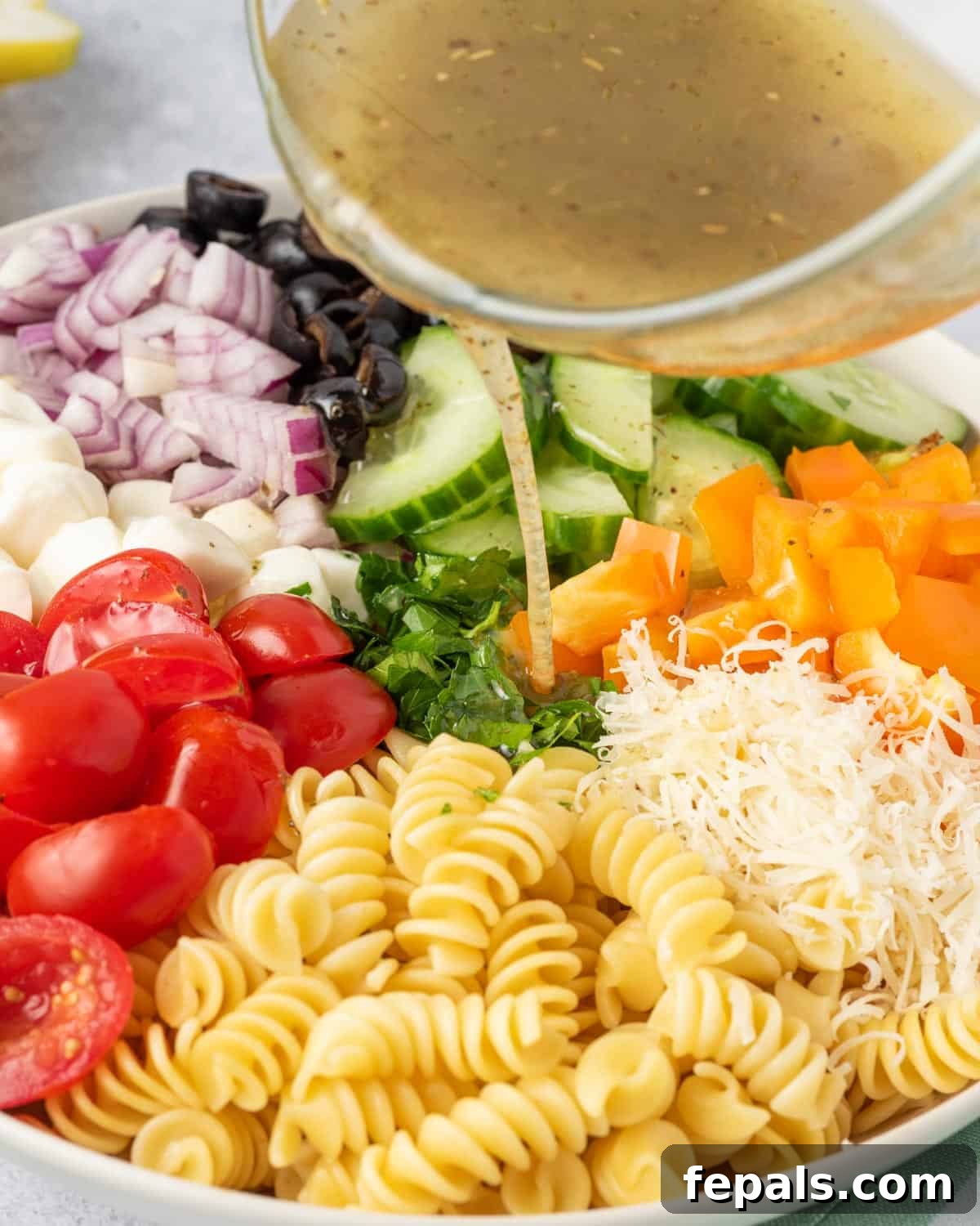Zesty Italian Pasta Salad 9 The homemade Italian dressing being poured generously over the mixed pasta and vegetables.