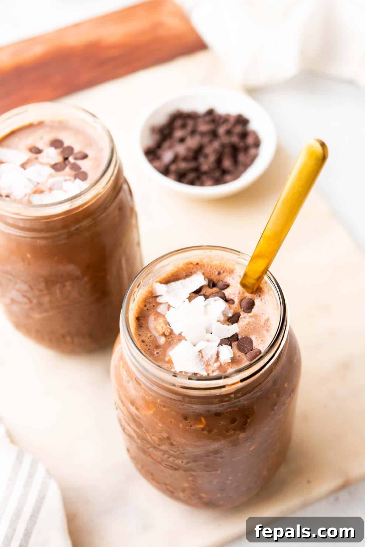 Two jars of overnight oats with peanut butter and chocolate, generously topped with coconut and chocolate chips