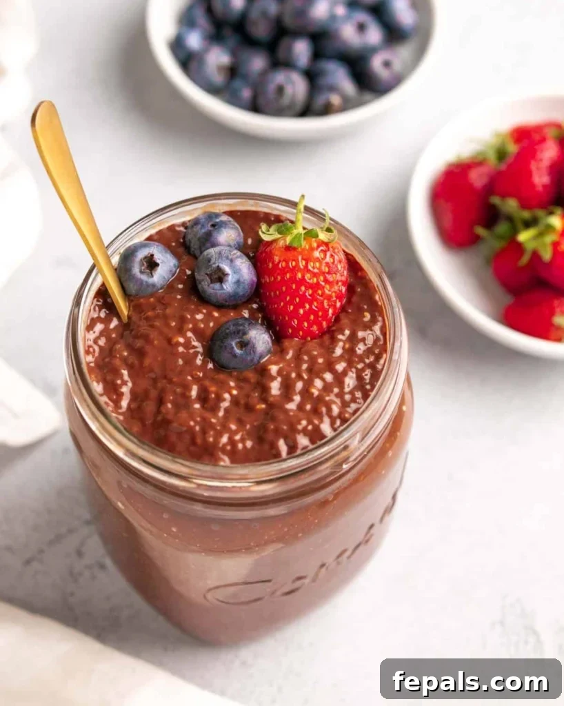 chocolate chia pudding in a jar topped with berries and a gold spoon in the jar