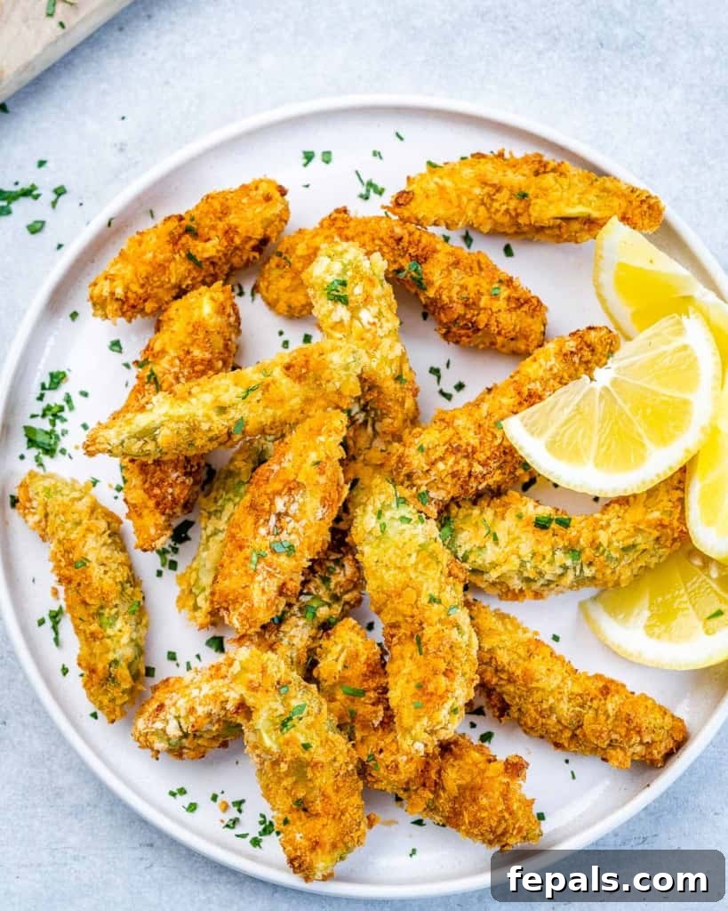 Avocado Golden Fingers 6 top view of baked avocado fries with lemon slices on a white plate, ready to serve
