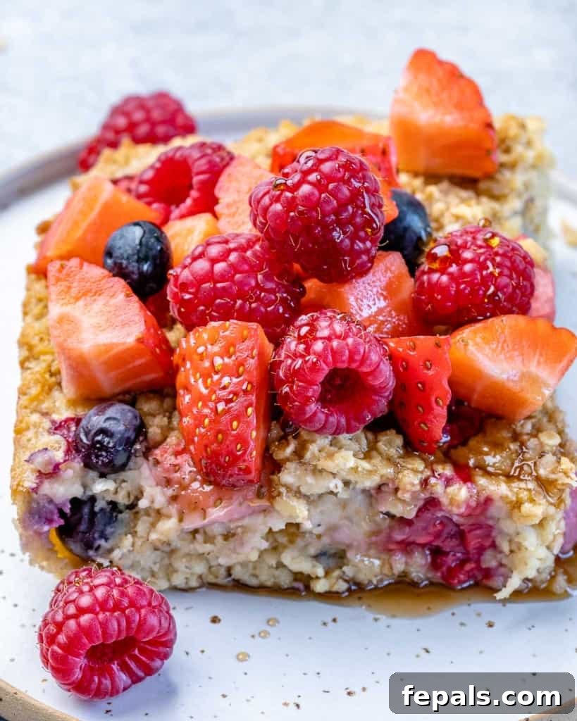 A delectable slice of baked oatmeal, generously topped with fresh berries, presented on a plate, ready to be enjoyed.