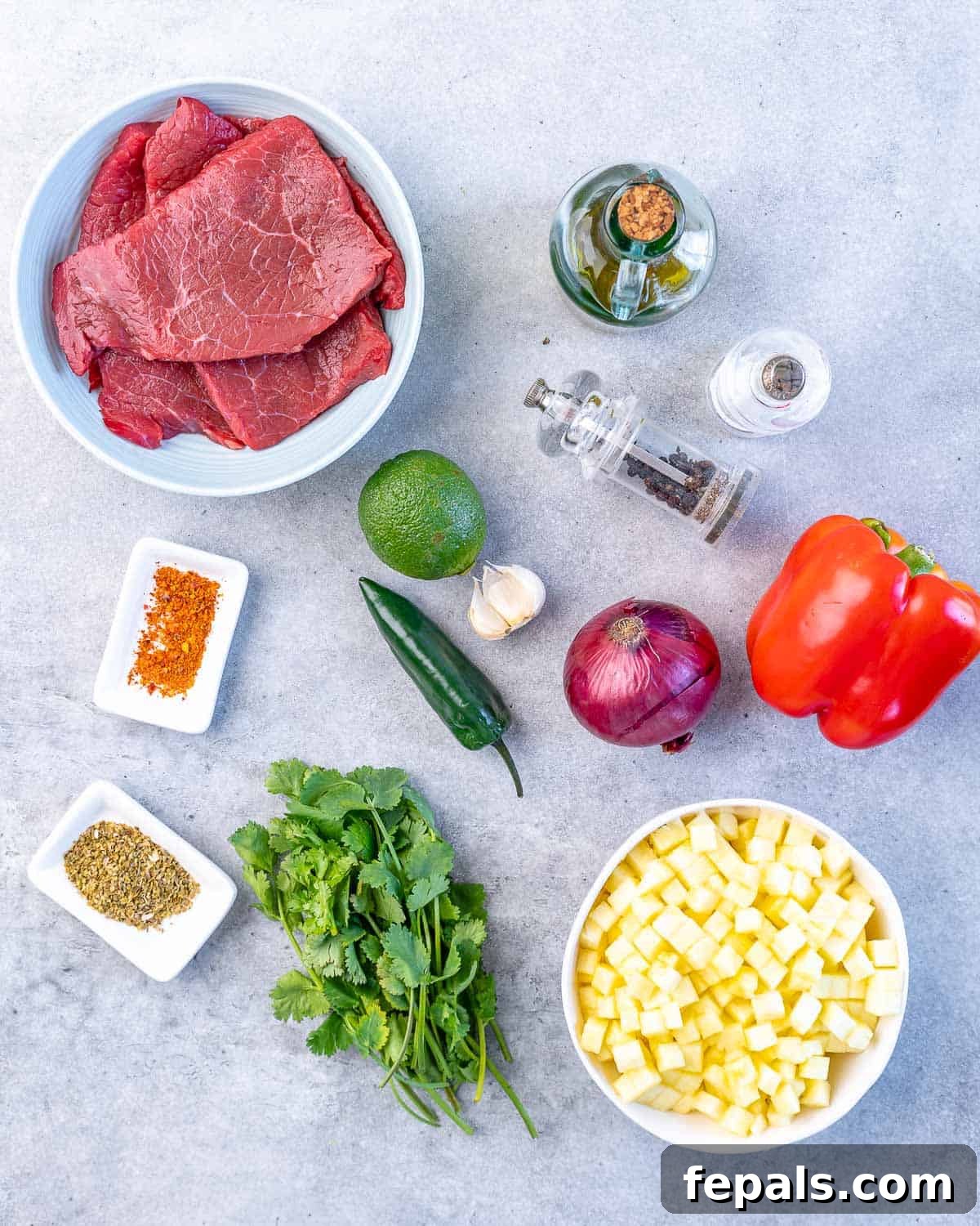 Grilled Skirt Steak Recipe with Pineapple Salsa pineapple, salt, pepper, olive oil, bell pepper, red onion, jalapeno, garlic, lime, cilantro, oregano, chili flakes, and skirt steak on grey surface
