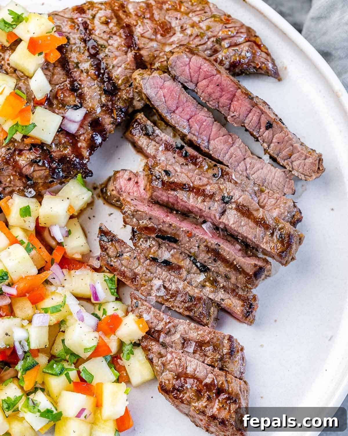 Perfectly Grilled Flank Steak Recipe with Fresh Pineapple Salsa close view of grilled flank steak on white plate with pineapple salsa recipe