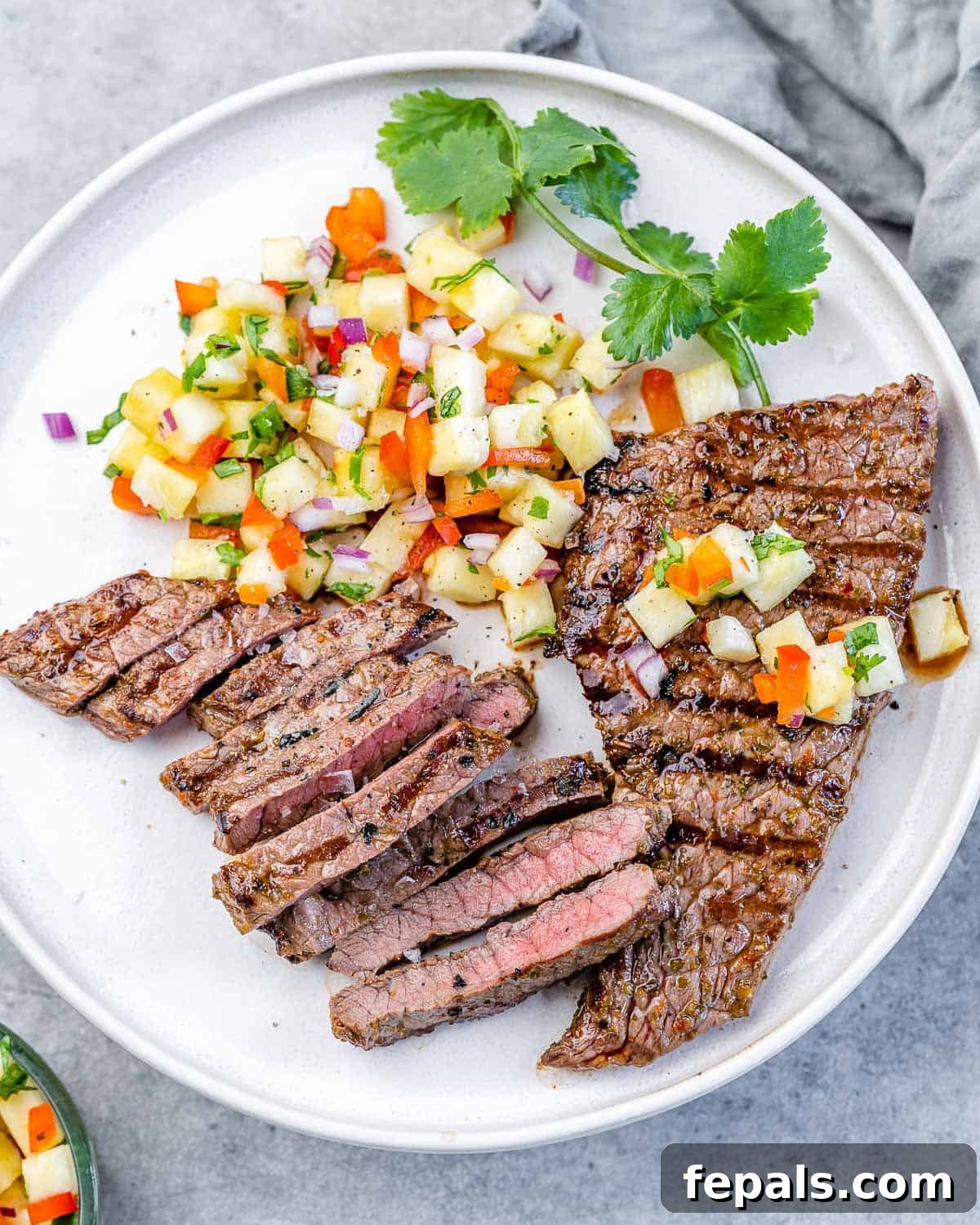 Perfect Grilled Steak with Pineapple Salsa top view of grilled skirt steak on white plate with pineapple salsa