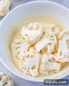 Perfectly Crispy Air Fryer BBQ Cauliflower Wings 16 cauliflower floret in the buttermilk mixture in a white bowl