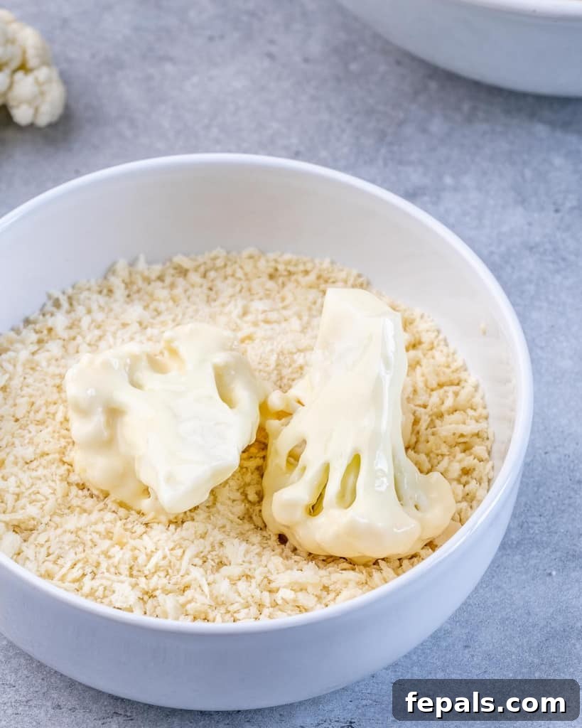 Cauliflower being dipped into breadcrumbs.