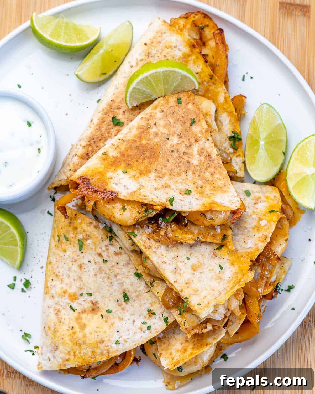 Healthy Shrimp Quesadilla Recipe Presentation Top view of a single shrimp quesadilla, sliced into wedges, on a pristine white plate, showcasing the golden tortilla and rich filling.