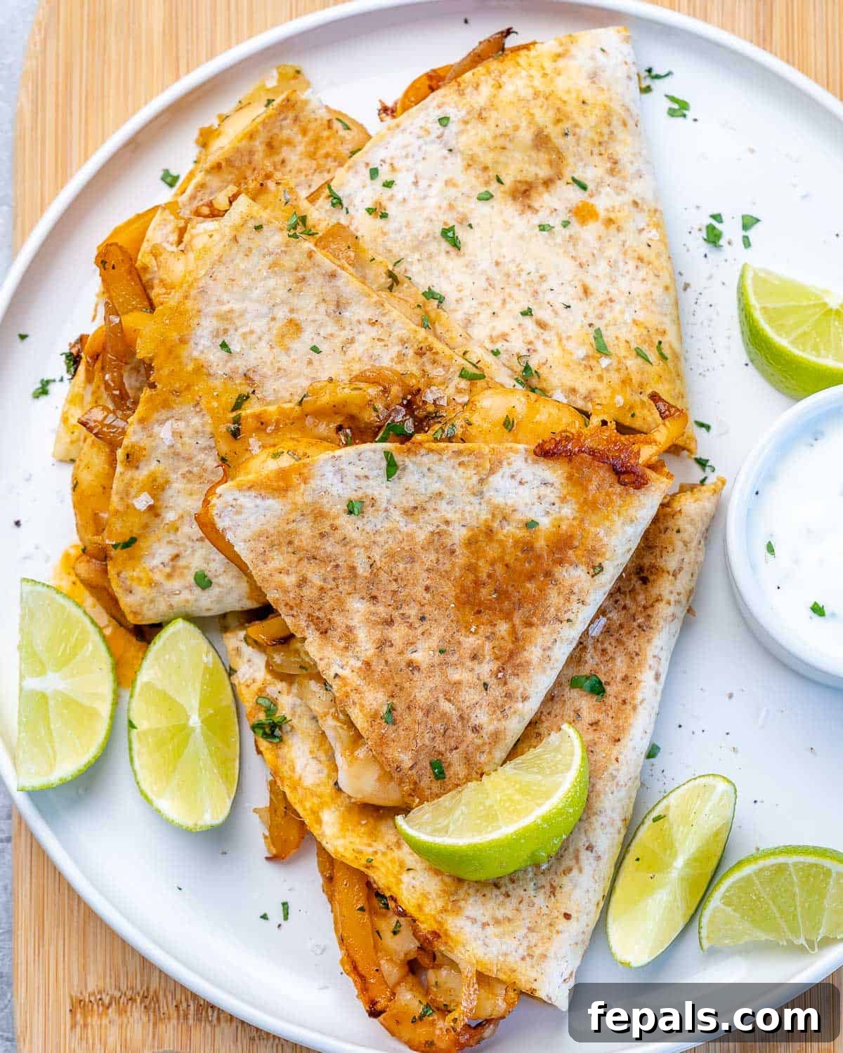 Healthy Seafood Quesadillas for Any Occasion Top view of several shrimp quesadillas neatly arranged on a white plate, garnished with fresh lime wedges for a vibrant presentation.