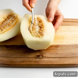 scooping the seeds out of the cantaloupe with a spoon
