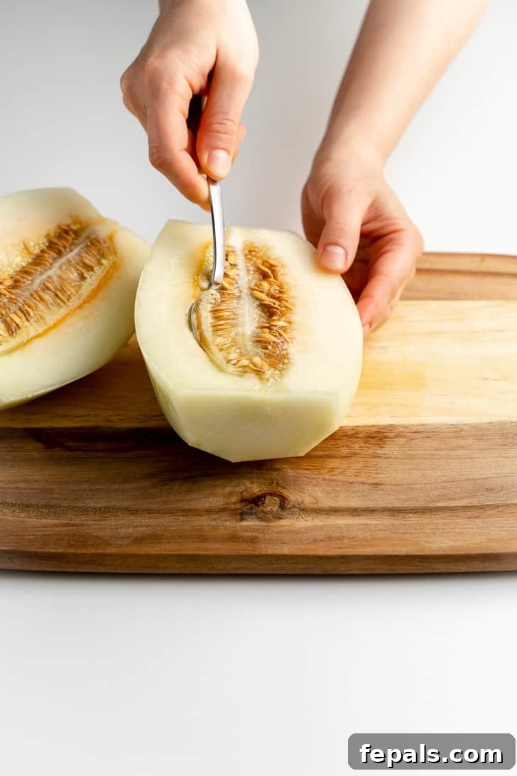 scooping the seeds out of the cantaloupe with a spoon