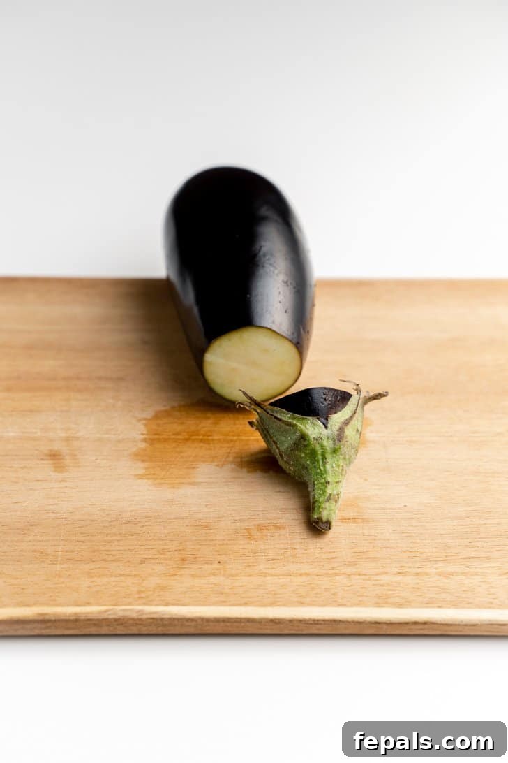 Stem Removed from Eggplant for Slicing Eggplant with the stem precisely cut off, revealing the white interior.