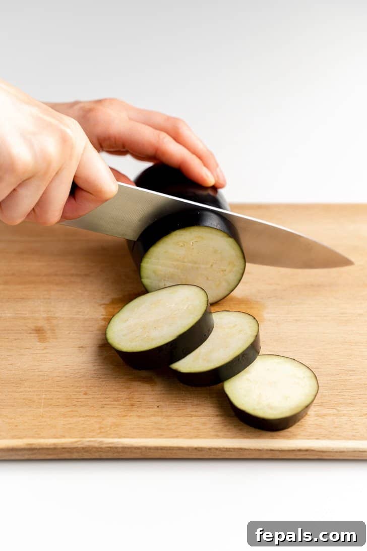 Precise Eggplant Slices for Cooking Close-up of a knife making even slices to create eggplant rounds.