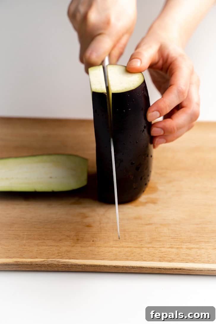 Cutting Eggplant into Halves Slicing an eggplant in half lengthwise with a sharp knife.