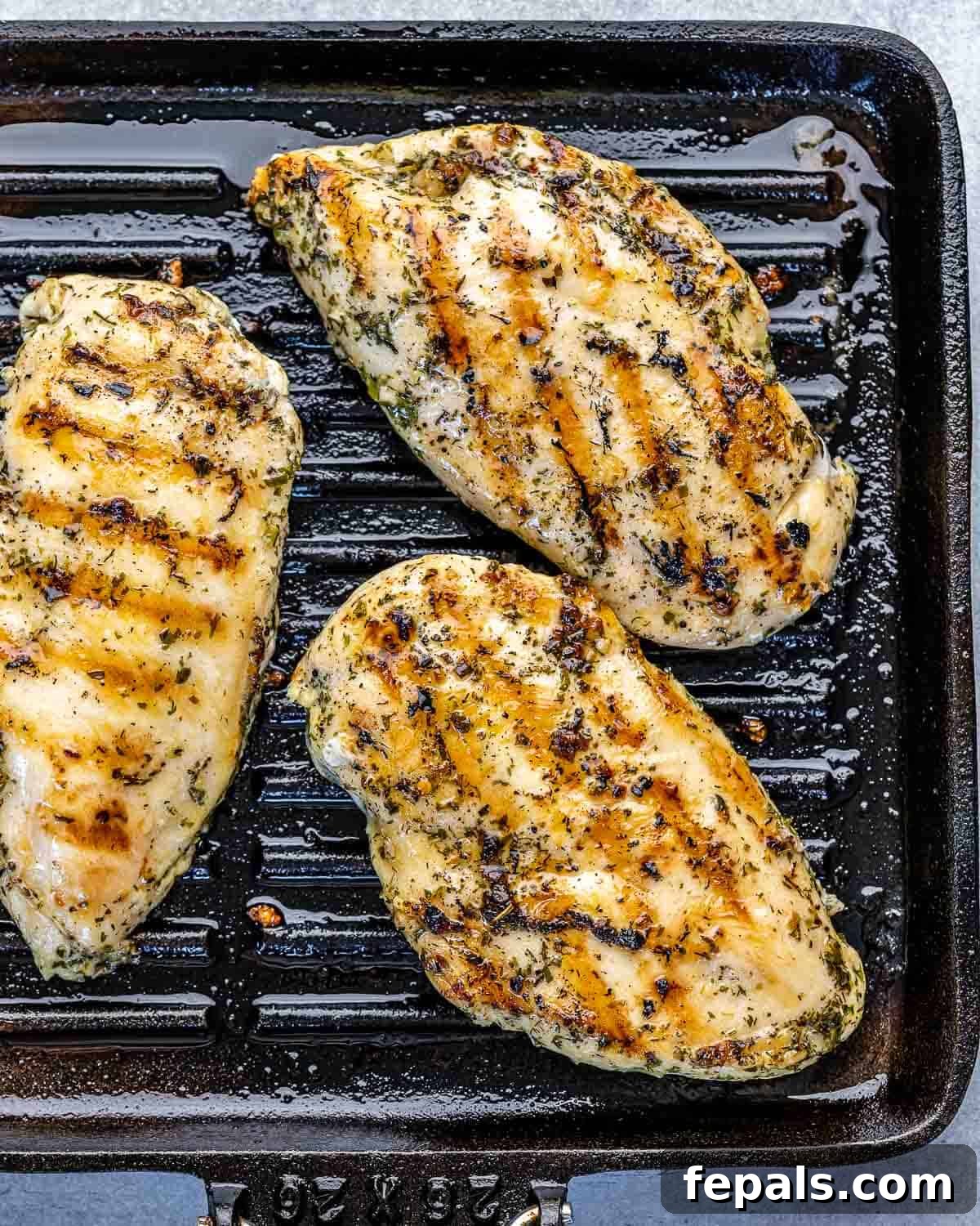 Another view of the chicken breasts grilling, flipped to reveal beautifully charred grill marks and a succulent interior.