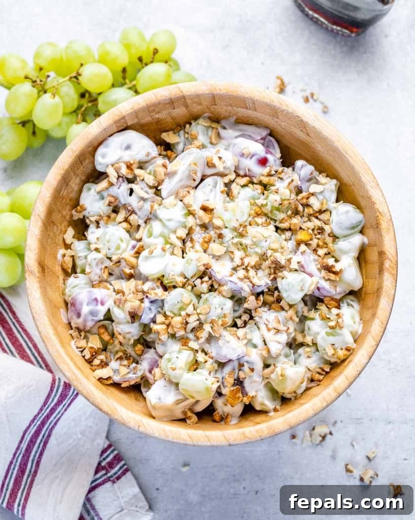 Top view of creamy grape salad with walnuts in a brown bowl, ready to be served as a refreshing side dish.