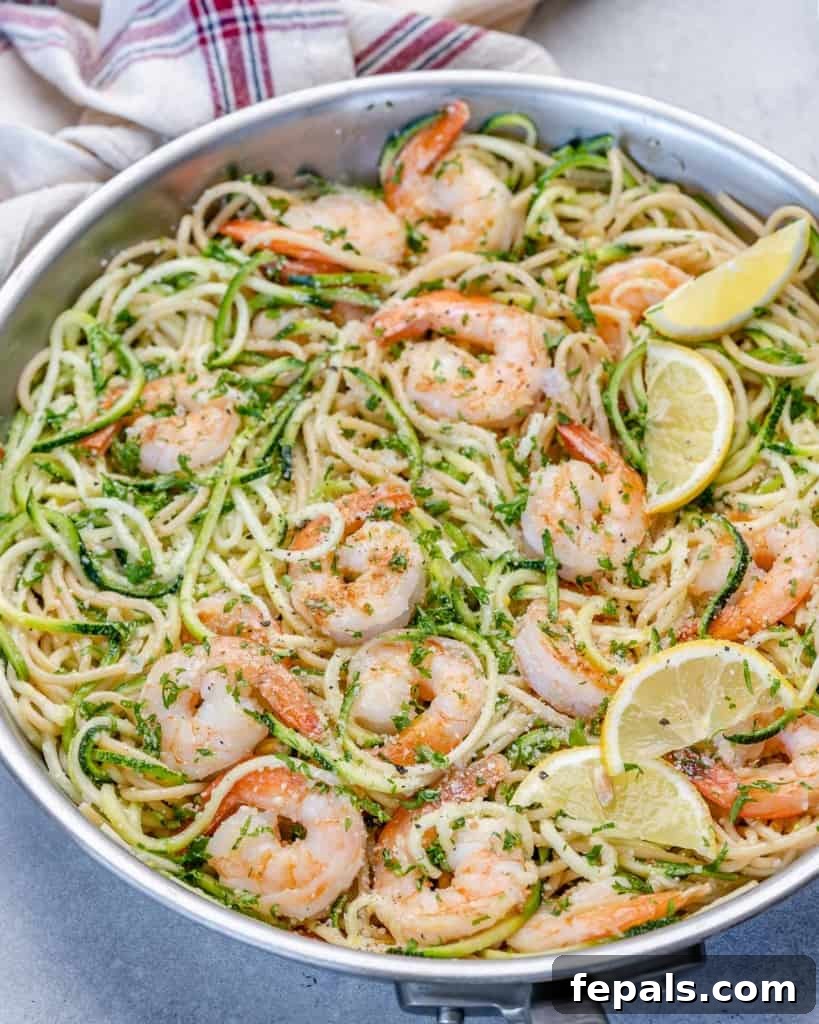 Zesty Lemon Shrimp Pasta with Zucchini Noodles 2 Vibrant lemon garlic shrimp pasta with zucchini noodles, fresh lemon wedges, and parsley in a large skillet, ready to serve.