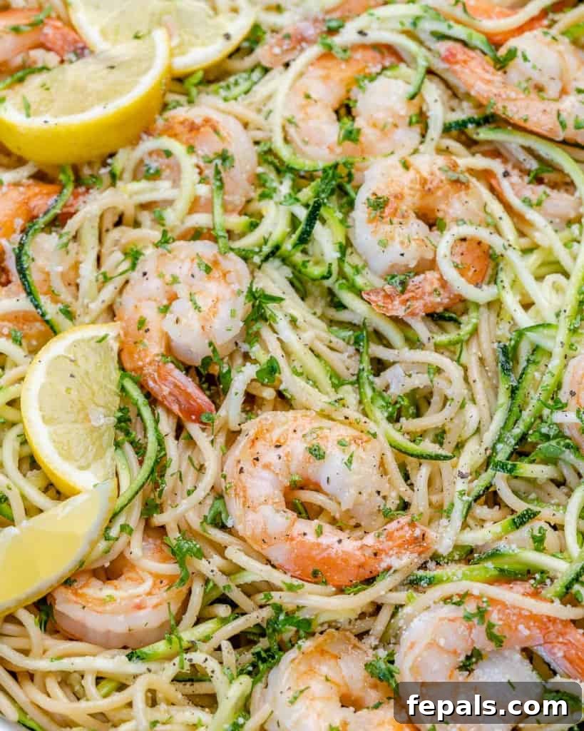 Zesty Lemon Shrimp Pasta with Zucchini Noodles 11 Top-down shot of a pan featuring lemon garlic shrimp, pasta, fresh lemon slices, vibrant parsley, and zucchini noodles, perfectly mixed.