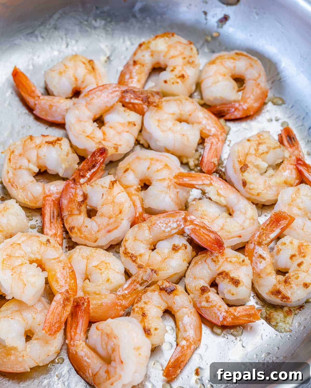 Zesty Lemon Shrimp Pasta with Zucchini Noodles 6 Shrimp cooking in a skillet, turning pink and opaque, ready to be added to the pasta dish.