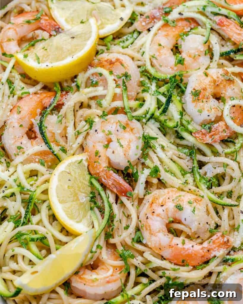 Zesty Lemon Shrimp Pasta with Zucchini Noodles 9 Lemon garlic shrimp pasta and zucchini noodles in a pan, garnished with fresh lemon slices and parsley.