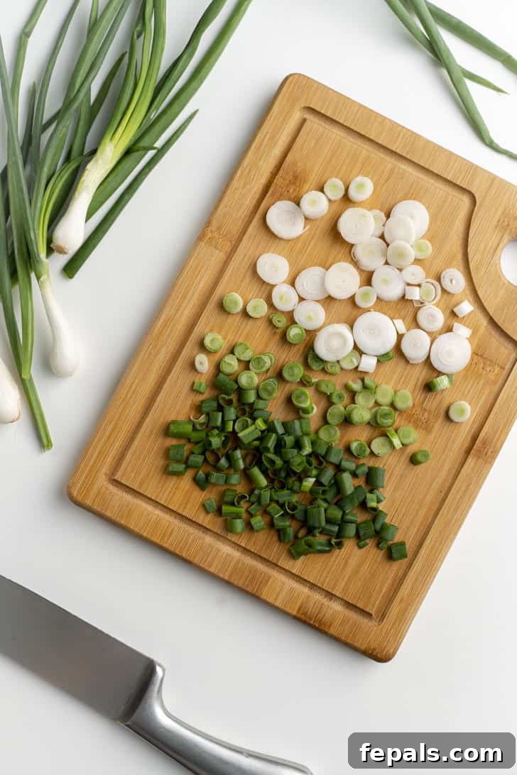 A generous pile of freshly sliced scallions spread across a wooden cutting board, ready for culinary use