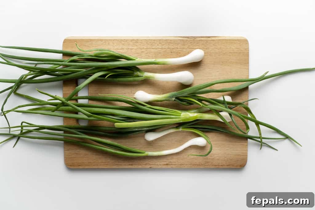Fresh scallions laid out neatly on a clean wooden cutting board, ready for preparation